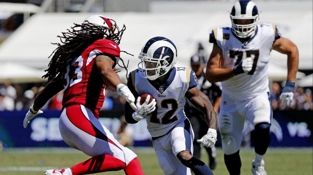 Rams wide receiver Brandin Cooks (12) makes a cut to avoid the tackle of Arizona Cardinals defensive back Tre Boston (33) in the first half at the Coliseum on Sept. 16, 2018.