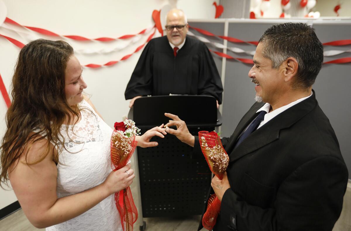Miguel Rodriguez places a ring on the finger of Donna Rodriguez as John Schatzel, deputy commissioner of civil marriages, officiates on Valentine's Day at the office of the Los Angeles County registrar-recorder/county clerk in Norwalk.
