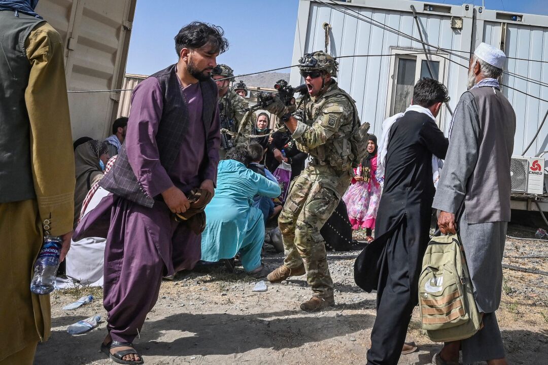 یک سرباز آمریکایی تفنگ خود را به طرف یک افغان در فرودگاه کابل نشانه می رود.