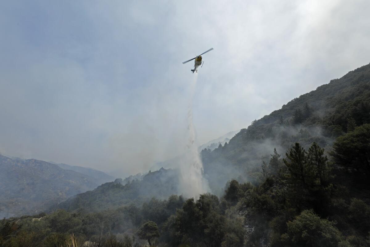 A helicopter makes a water drop while fighting the Bobcat fire.