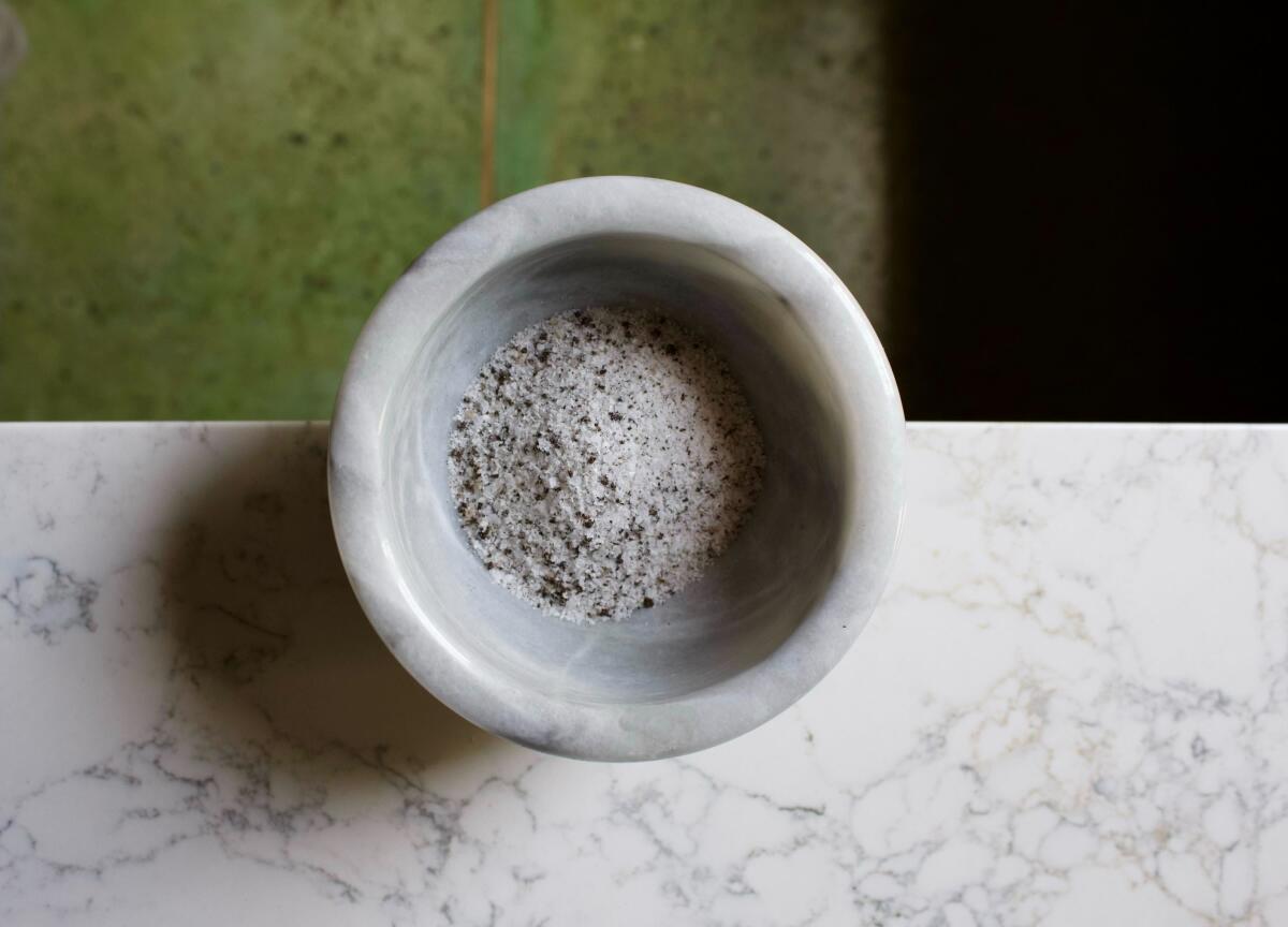 An overhead photo of a marble bowl full of vanilla-flecked salt 