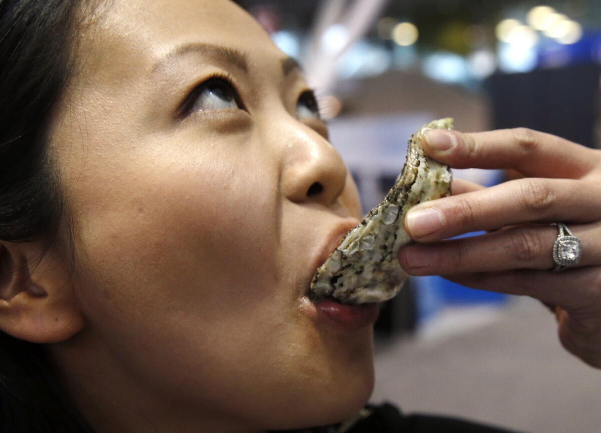 Oyster specialist Julie Qiu enjoys a sample from Blue Island Oyster Farms of New York at the 33rd Seafood Expo North America in Boston last month.