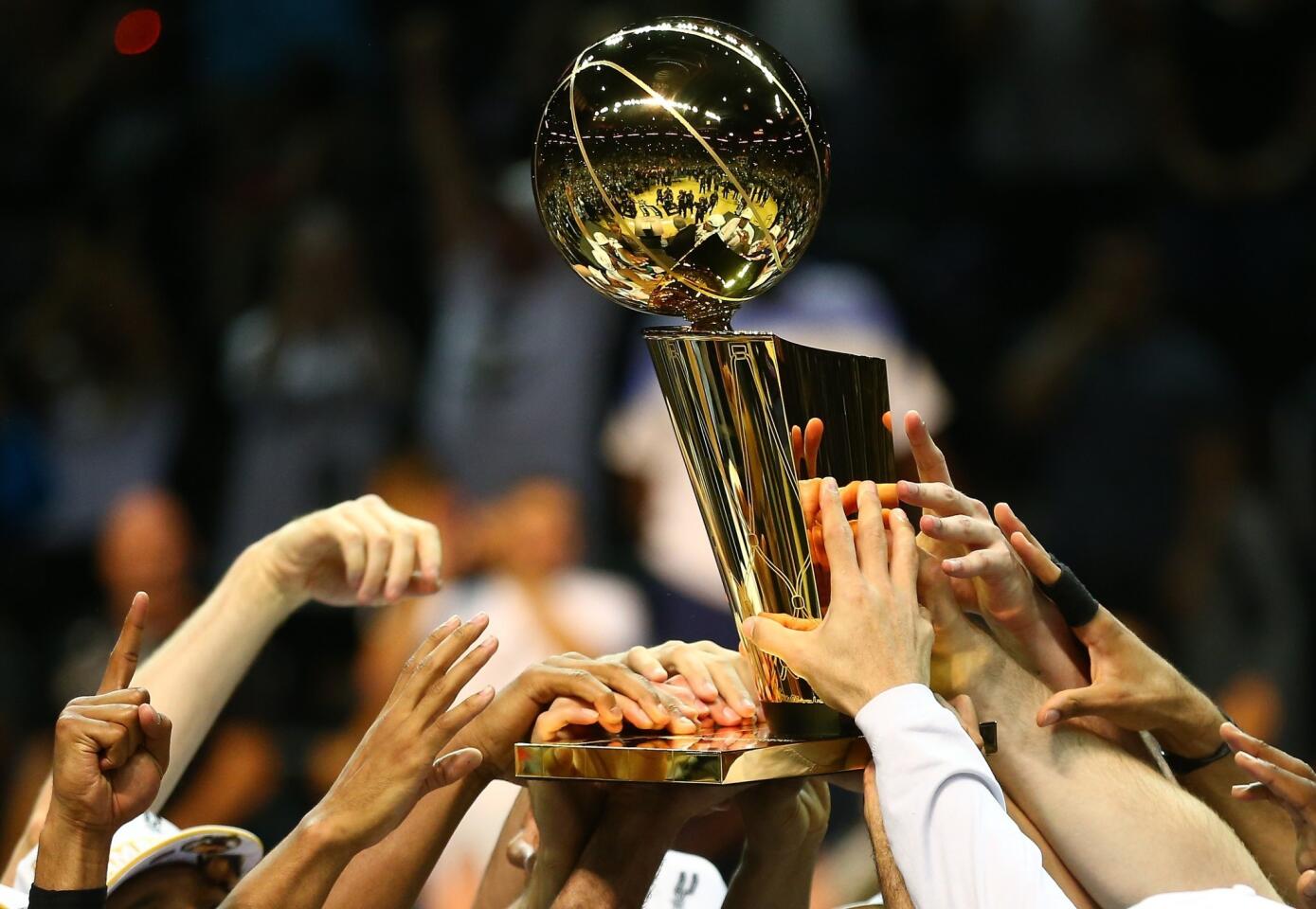 San Antonio Spurs players hold the Larry O'Brien trophy after defeating the Heat, 4-1, in the NBA Finals in June.