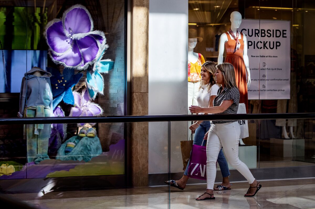 Two women shop inside South Coast Plaza on May 13 in Costa Mesa.