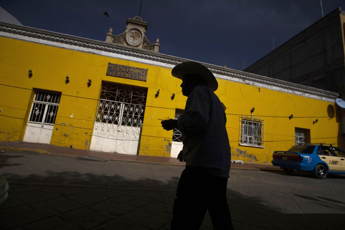FILE - A customer leaves a bank where people receive international money wires, in Acatlan de Osorio, Mexico, June 27, 2020. Mexico’s central bank said Tuesday, Feb. 1, 2022, remittances — the money migrants send home to their relatives — grew by 27.1% in 2021 to total about $51.6 billion for the year as a whole. (AP Photo/Fernando Llano, File)