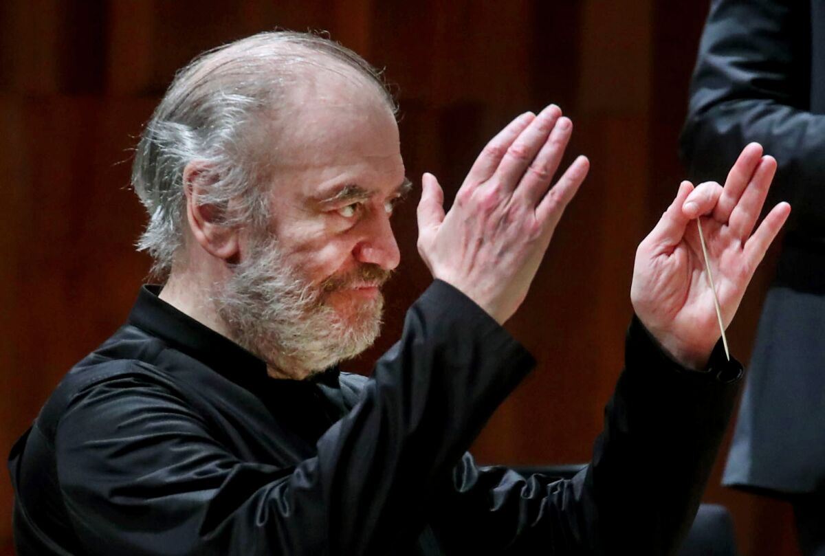 A conductor raises his arms