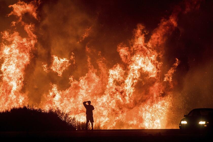 FILE - In this Dec. 6, 2017, file photo, a motorist on Highway 101 watches flames from the Thomas Fire, the largest wildfire on record in California, leap above the roadway north of Ventura, Calif. On Thursday, May 10, 2018, Gov. Jerry Brown signed an executive order that aims to reduce the dangers of wildfires following some of the deadliest and most destructive blazes in state history. The order calls for accelerating forest management procedures such as cutting back dense stands of trees, setting controlled fires to burn out thick brush and reforesting damaged areas. (AP Photo/Noah Berger, File)