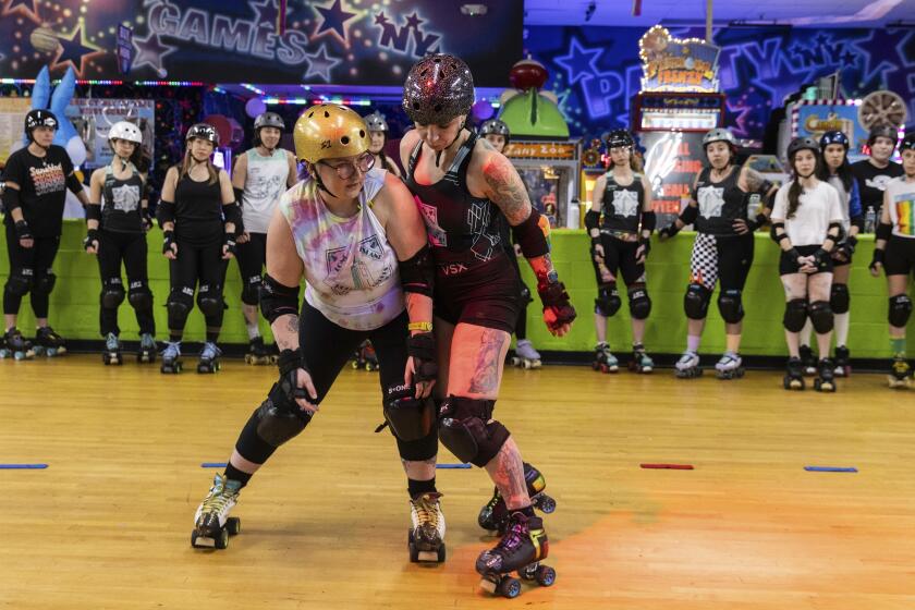 FILe - Caitlin Carroll, right, demonstrates skills, Tuesday, March 19, 2023, at United Skates of America in Seaford, N.Y. (AP Photo/Jeenah Moon, File)