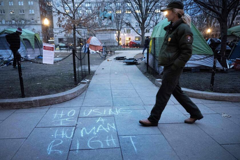 A member of the US National Park Service walks past a homeless encampment before it is cleared from McPherson Square, two blocks from the White House, on February 15, 2023 in Washington, DC. - Some 56 people live in the federal park, which is being cleared ahead of the initial April schedule due to safety concerns. (Photo by Brendan Smialowski / AFP) (Photo by BRENDAN SMIALOWSKI/AFP via Getty Images)