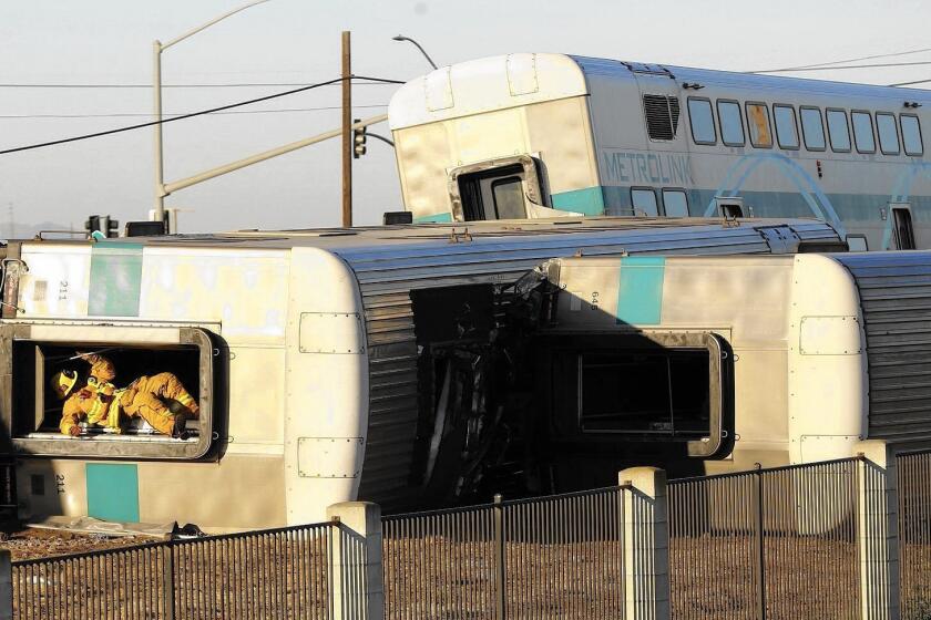 A firefighter climbs out of an overturned Metrolink train car that derailed in Oxnard on Feb. 24.