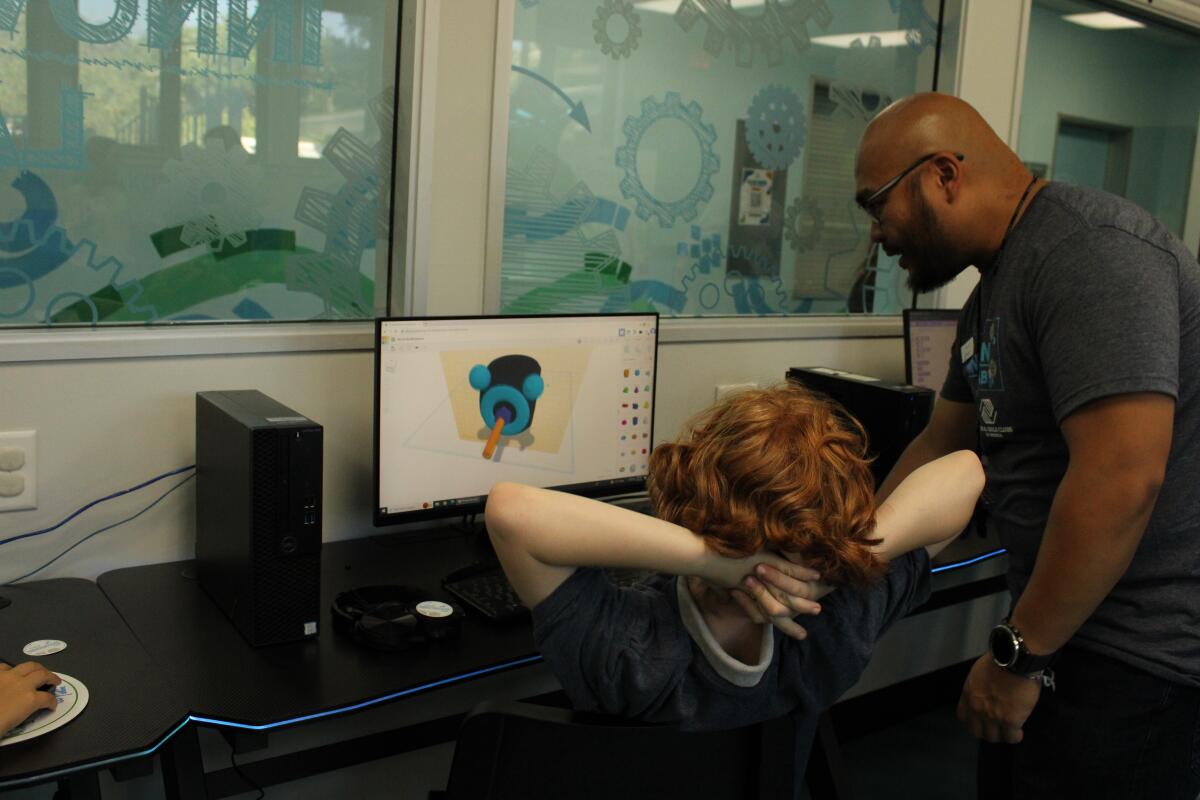 An instructor reviews a club member's work in the Cox Innovation Lab.