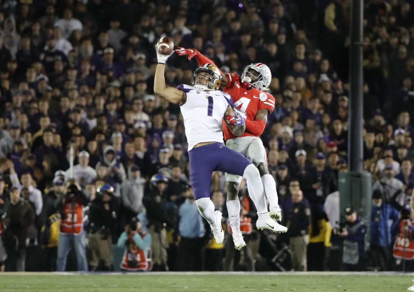 Washington tight end Hunter Bryant (1) leaps up to make a one-handed catch against Ohio State safety Jordan Fuller (4) as the Huskies try to make a comeback in the fourth quarter.