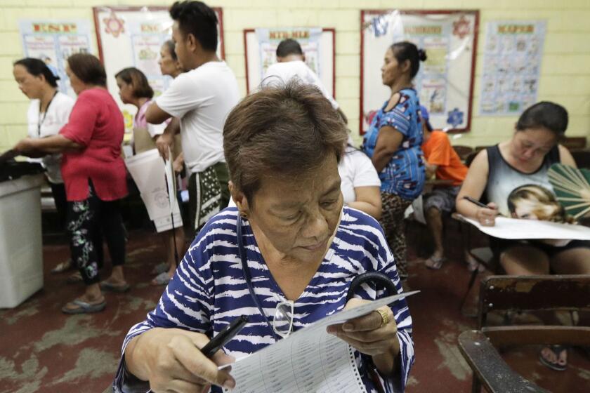 A Filipino checks her ballot as she votes at a polling center at the Manuel L. Quezon elementary school, Manila, Philippines, Monday, May 13, 2019. Filipinos began voting in midterm elections highlighted by a showdown between President Rodrigo Duterte's allies who aim to dominate the Senate and an opposition fighting for check and balance under a leader they regard as a looming dictator. (AP Photo/Aaron Favila)