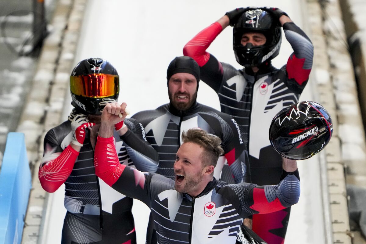 Justin Kripps, Ryan Sommer, Cam Stones and Benjamin Coakwell, of Canada, celebrate winning the bronze medal in the 4-manat the 2022 Winter Olympics, Sunday, Feb. 20, 2022, in the Yanqing district of Beijing. (AP Photo/Mark Schiefelbein)