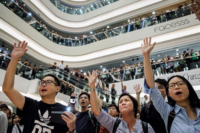 HONG KONG, CHINA -- THURSDAY, SEPTEMBER 12, 2019: People raise their open hand, chant "5 demands, not one less," and a sing-along to the newly minted crowdsourced anthem, ÒGlory to Hong Kong,Ó which has come to represent the pro-democracy protest movement at Times Square Shopping Center, in Hong Kong, on Sept. 12, 2019. Despite Chief Executive Carrie LamÕs bowing to the demonstratorsÕ key demand Ð withdrawal of a controversial extradition bill, demonstrators are now calling for Lam to immediately meet the rest of their demands. This includes an independent inquiry into policeÕs use of force, amnesty for those arrested, a halt on the use of the word ÒRiotÓ when describing the rallies, and lastly, calls for universal suffrage for the people of Hong Kong. (Marcus Yam / Los Angeles Times)