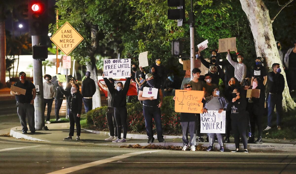 A small but vocal group of protesters occupy a corner of Bear Street and Sunflower Avenue in Costa Mesa.