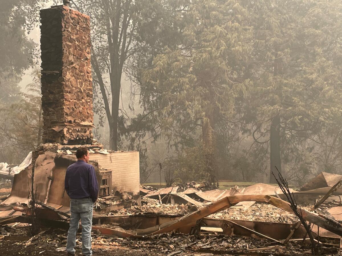 A man looks at the remains of a home incinerated in the Dixie fire.