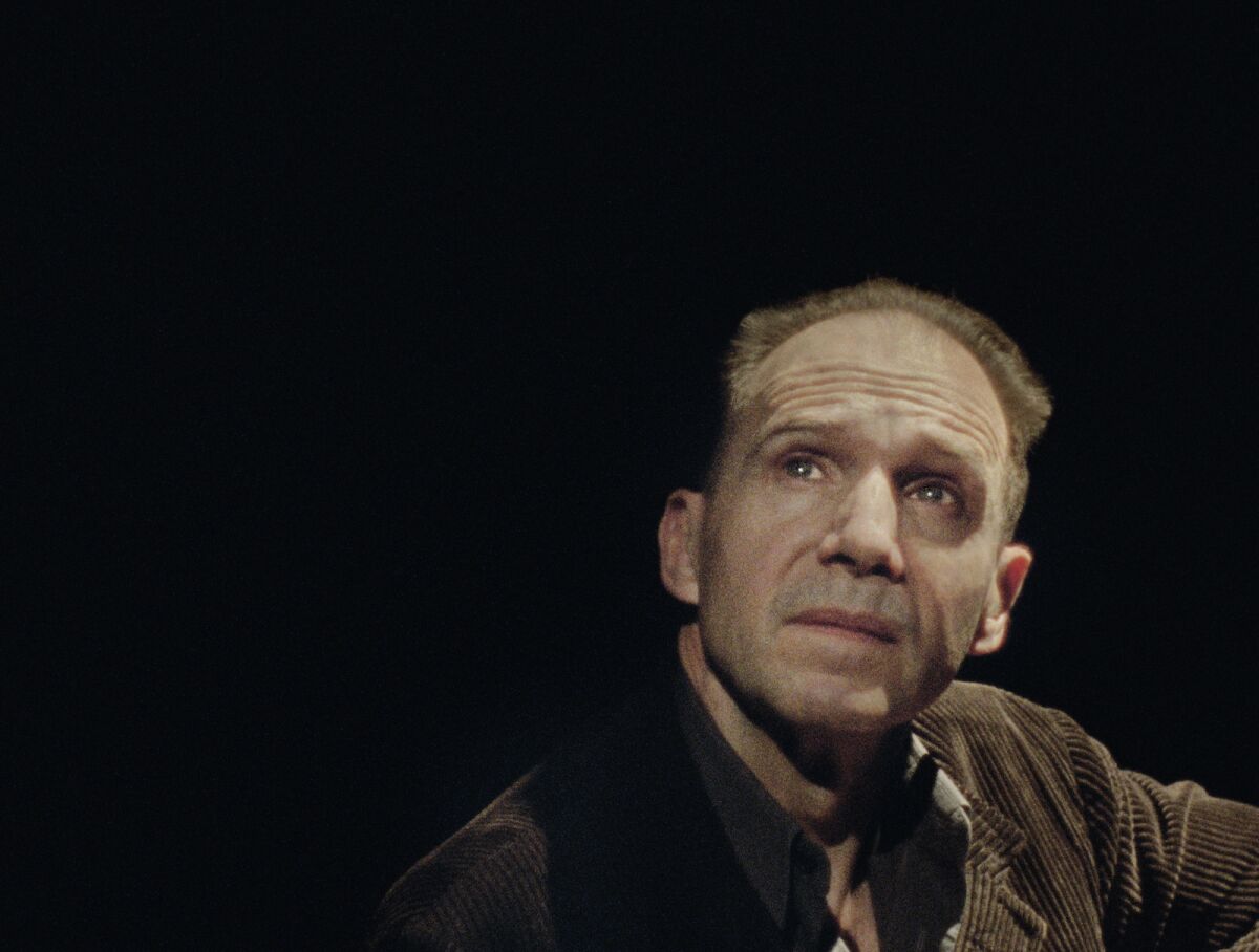 Ralph Fiennes looks up in front of a black background in the movie "Four Quartets."