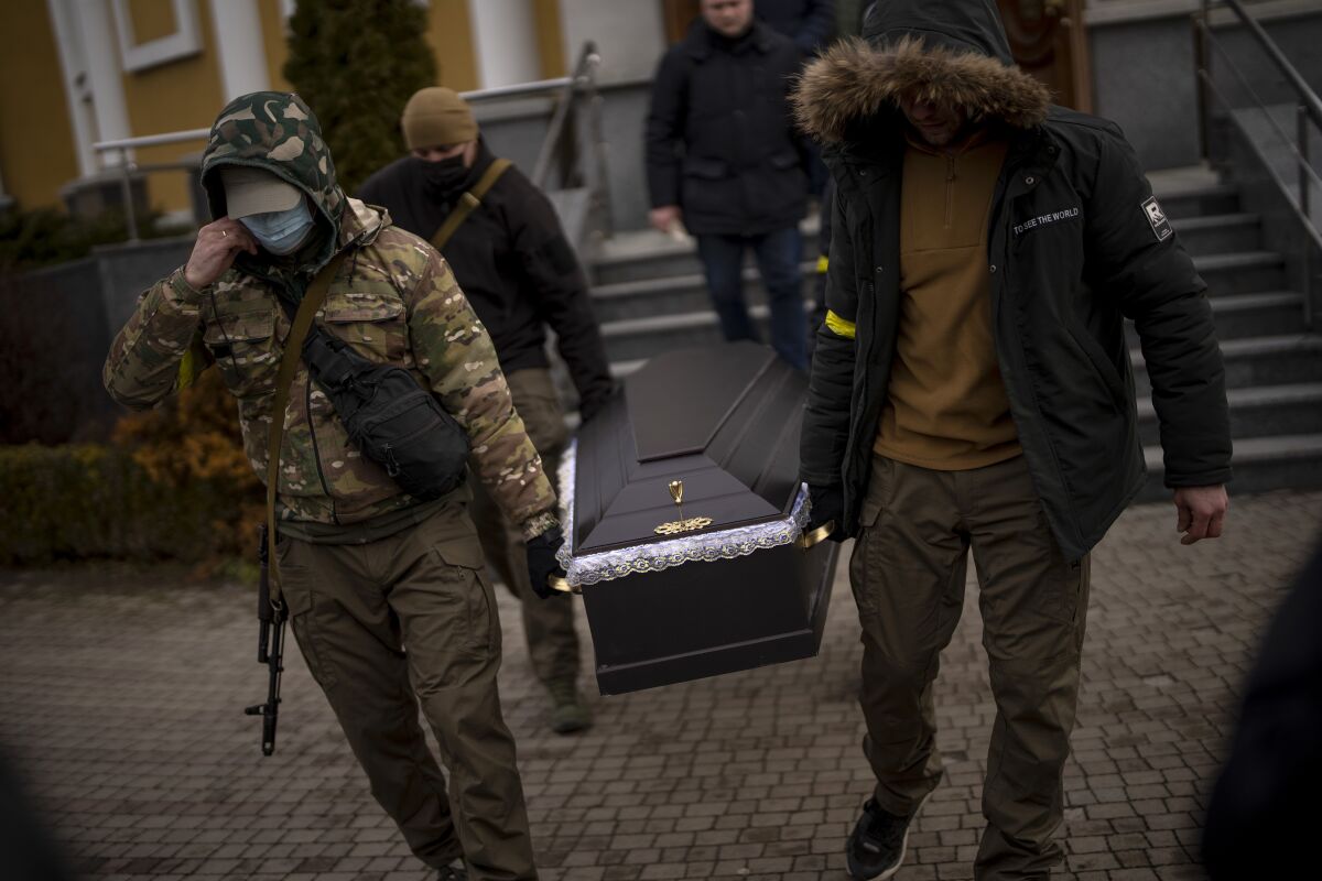 Militia men carry the coffin with the body of Volodymyr Nezhenets, 54, during his funeral in the city of Kyiv, Ukraine, Friday, March 4, 2022. A small group of reservists are burying their comrade, 54-year-old Volodymyr Nezhenets, who was one of three killed on Feb. 26 in an ambush Ukrainian authorities say was caused by Russian 'saboteurs'. (AP Photo/Emilio Morenatti)