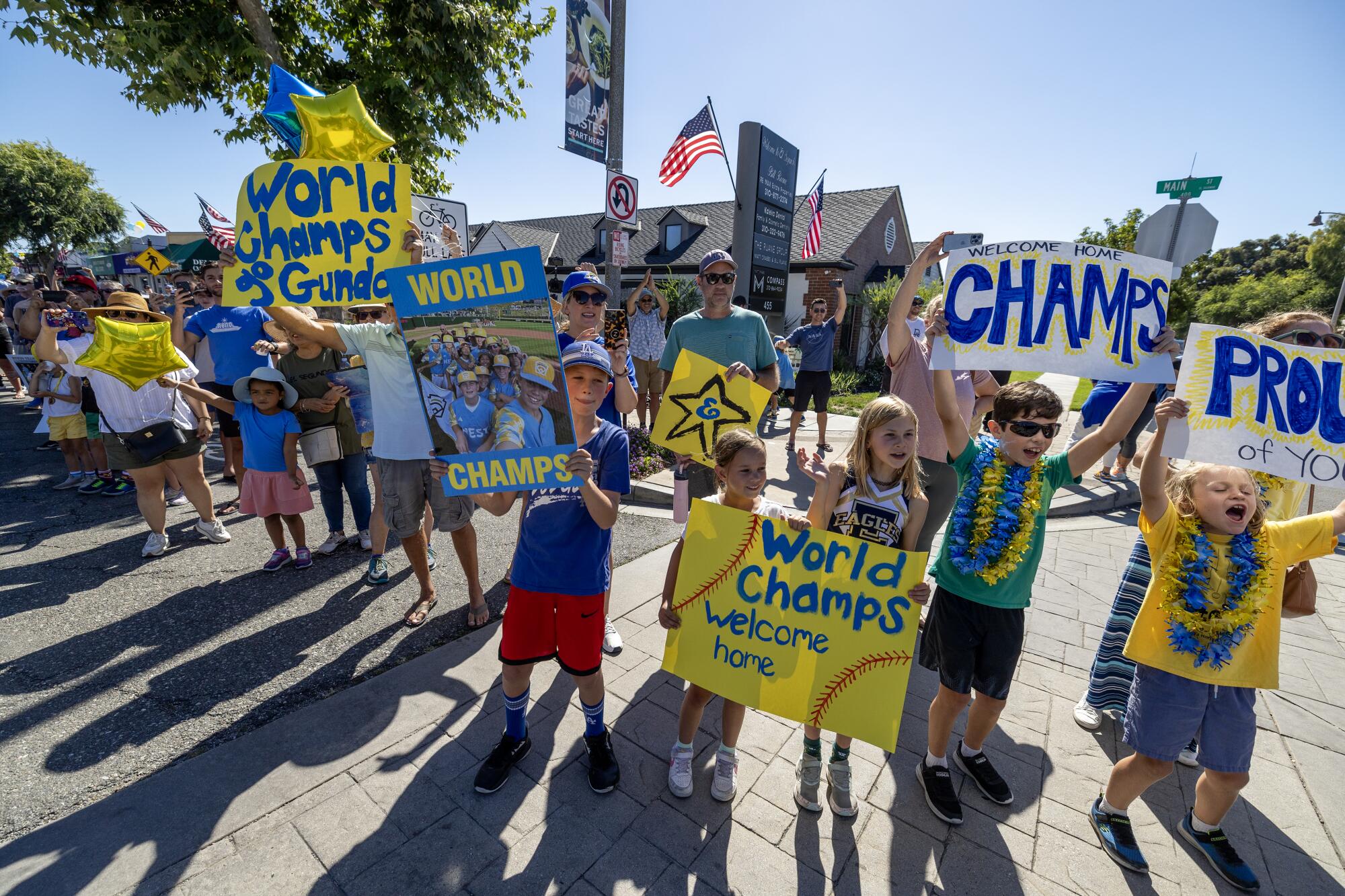 Cheering adults and children hold signs that say "Champs" and "Proud of you."