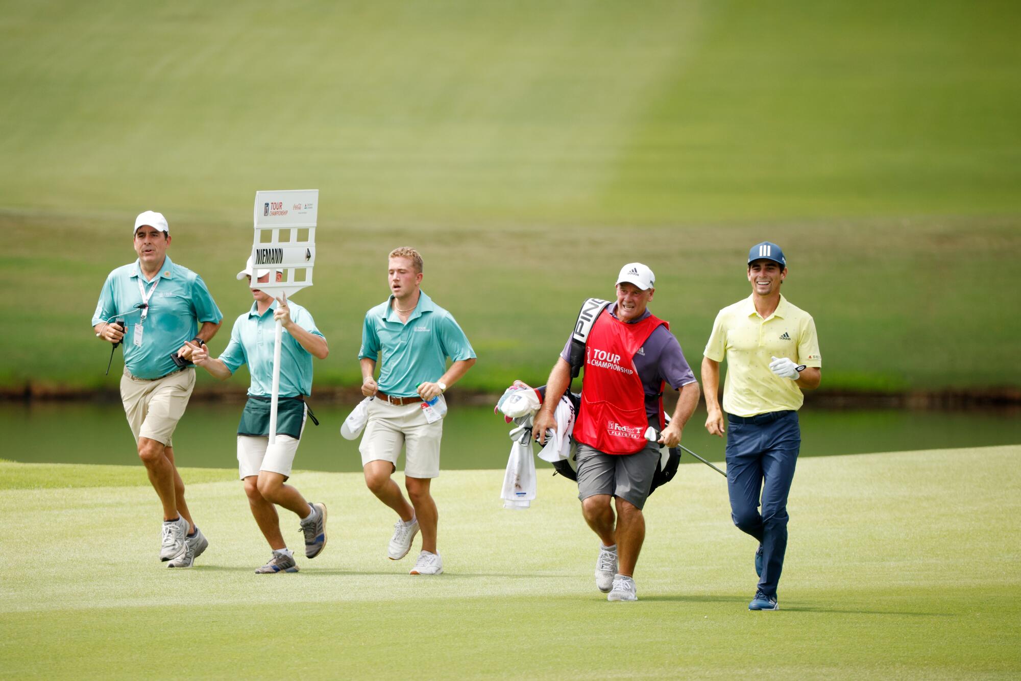 Joaquin Niemann, right, and caddie Gary Matthews, second from right, jog on No. 18 in a round that took 1 hour 53 minutes.