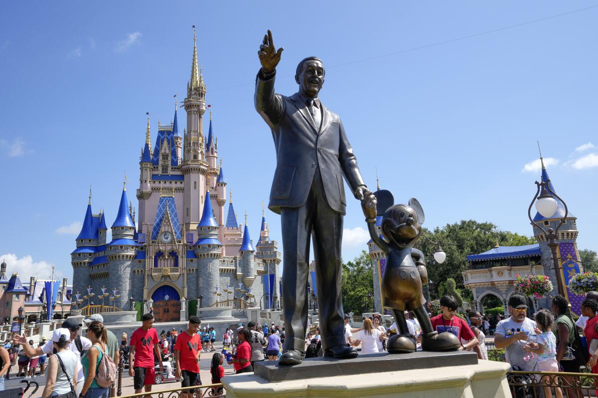 Visitantes del parque temático Magic Kingdom caminan cerca de una estatua de Walt Disney y Mickey Mouse