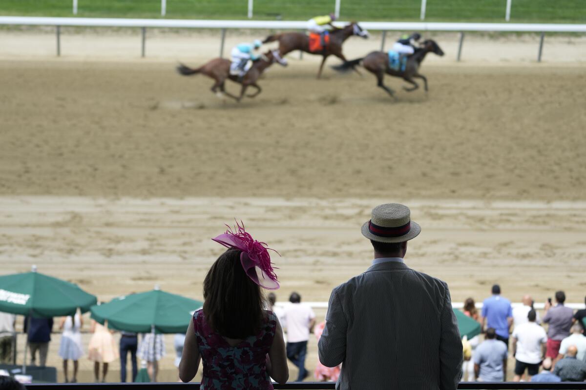 Spectators watch as horses run at Belmont Park on Saturday.