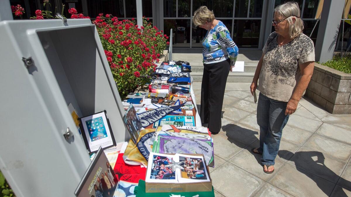 Newport-Mesa trustee Martha Fluor, left, and Donna Bunney look at items that will be placed in a time capsule at the Newport-Mesa Unified School District offices on Friday.