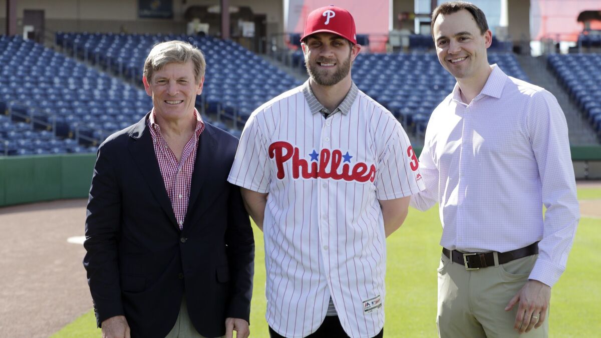 Bryce Harper, center, poses for a photo with Philadelphia Phillies managing partner John Middleton, left, and general manager Matthew Klentak after being introduced as a Phillies player during a news conference Saturday.