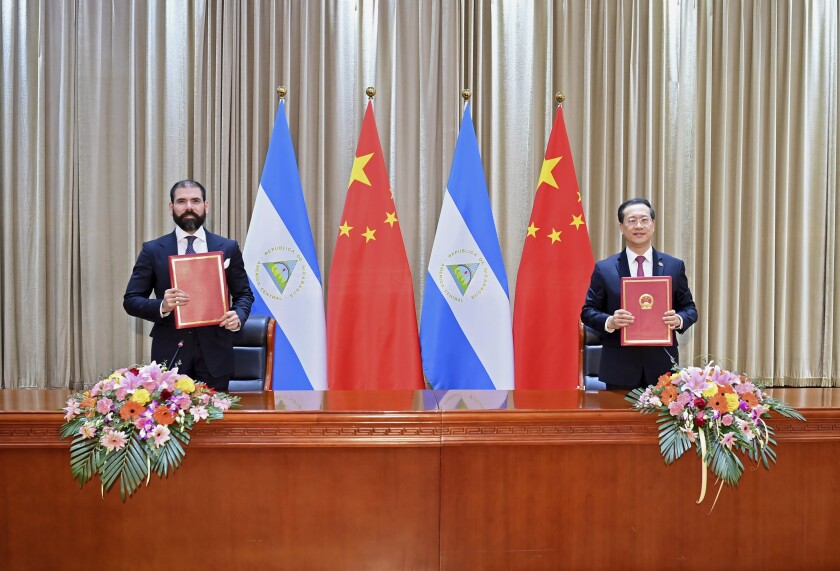 In this photo released by China's Xinhua News Agency, representatives from Nicaragua and China sign a joint communique on the resumption of diplomatic relations between the two countries in northern China's Tianjin Municipality, Friday, Dec. 10, 2021. Taiwan lost Nicaragua as a diplomatic ally after the Central American country said it would officially recognize only China, which claims self-ruled Taiwan as part of its territory. (Yue Yuewei/Xinhua via AP)