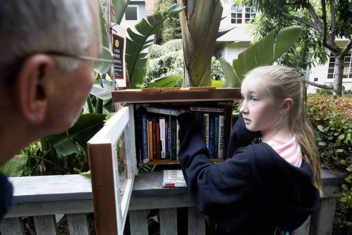 Fiona Sassoon, 10, gets some neighborly advice from David Dworski, left, on book selections at Dworski's diminutive outdoor library in Venice.