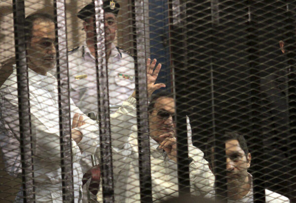 Former Egyptian President Hosni Mubarak waves at his supporters during a court appearance Saturday. Also in attendance were his sons: Alaa, right, and Gamal, left.