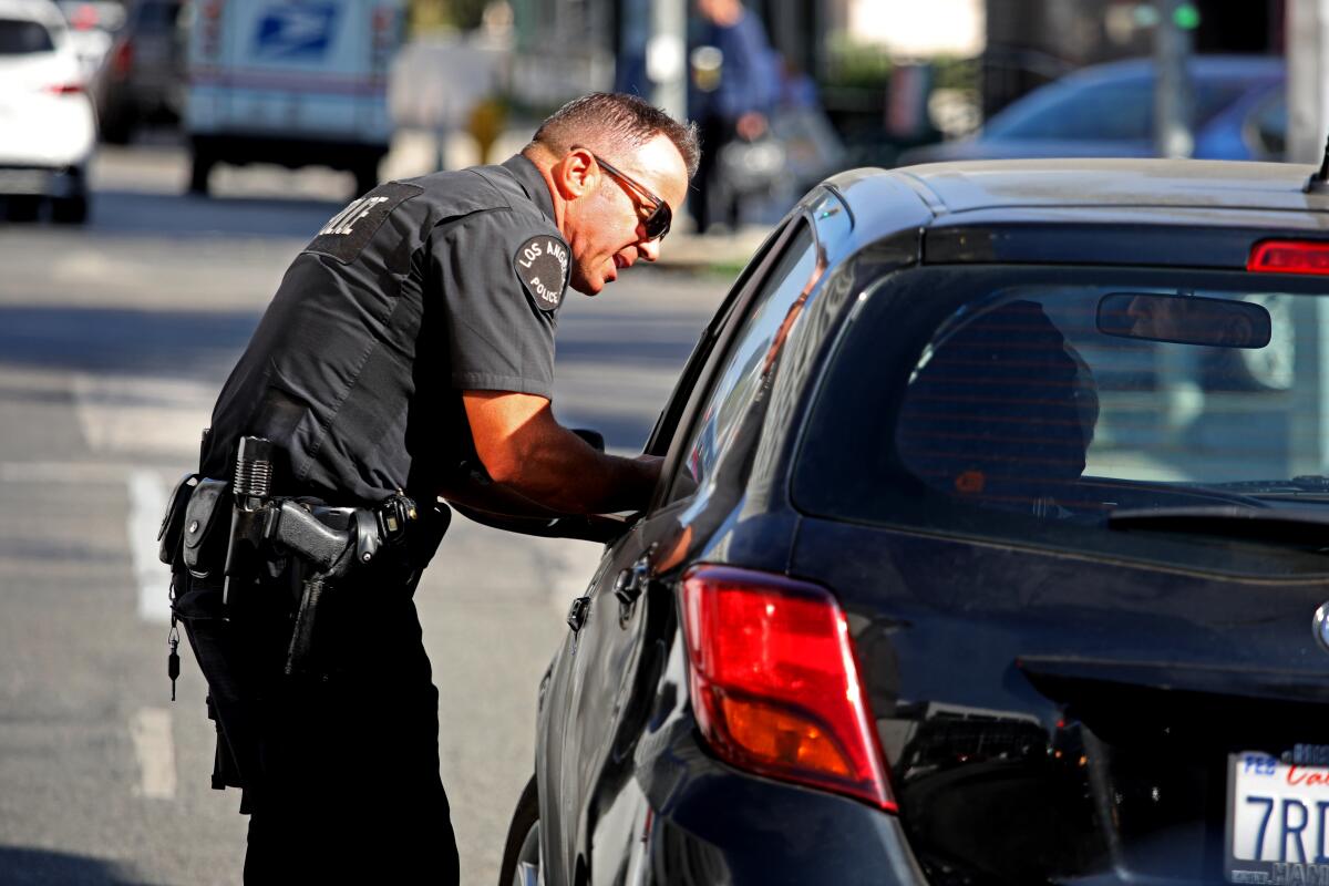 A police officer leans over to talk to a driver through their car window