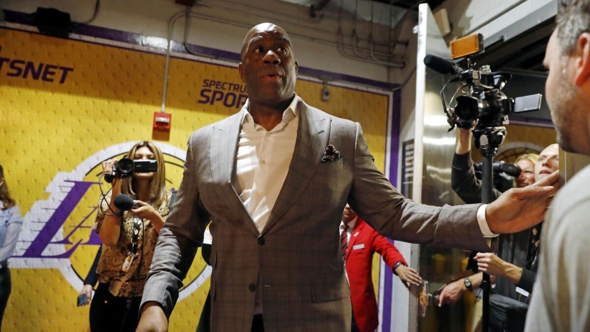 Magic Johnson navigates past media members after announcing on April 9 that he was stepping down as Lakers' president of basketball operations.