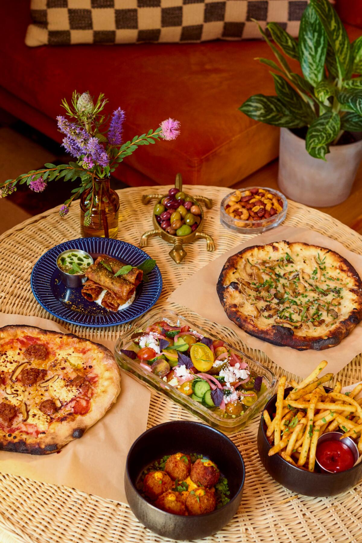 A spread of food from Justine's Wine Bar in Frogtown, including two pizzas, a side of fries, potato croquettes, and more.