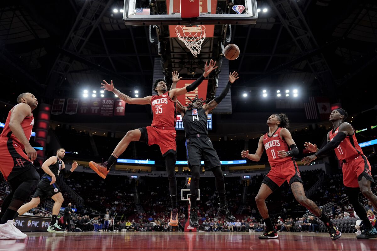 The Rockets' Christian Wood (35) and Clippers' Terance Mann (14) reach for a rebound