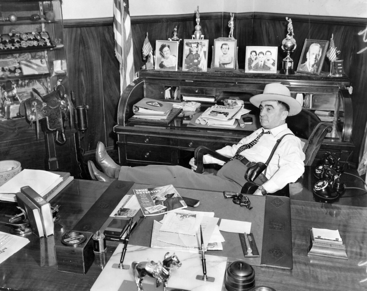 A 1943 file photo of Sheriff Eugene Biscailuz in his office with his feet up and a revolver on his desk.