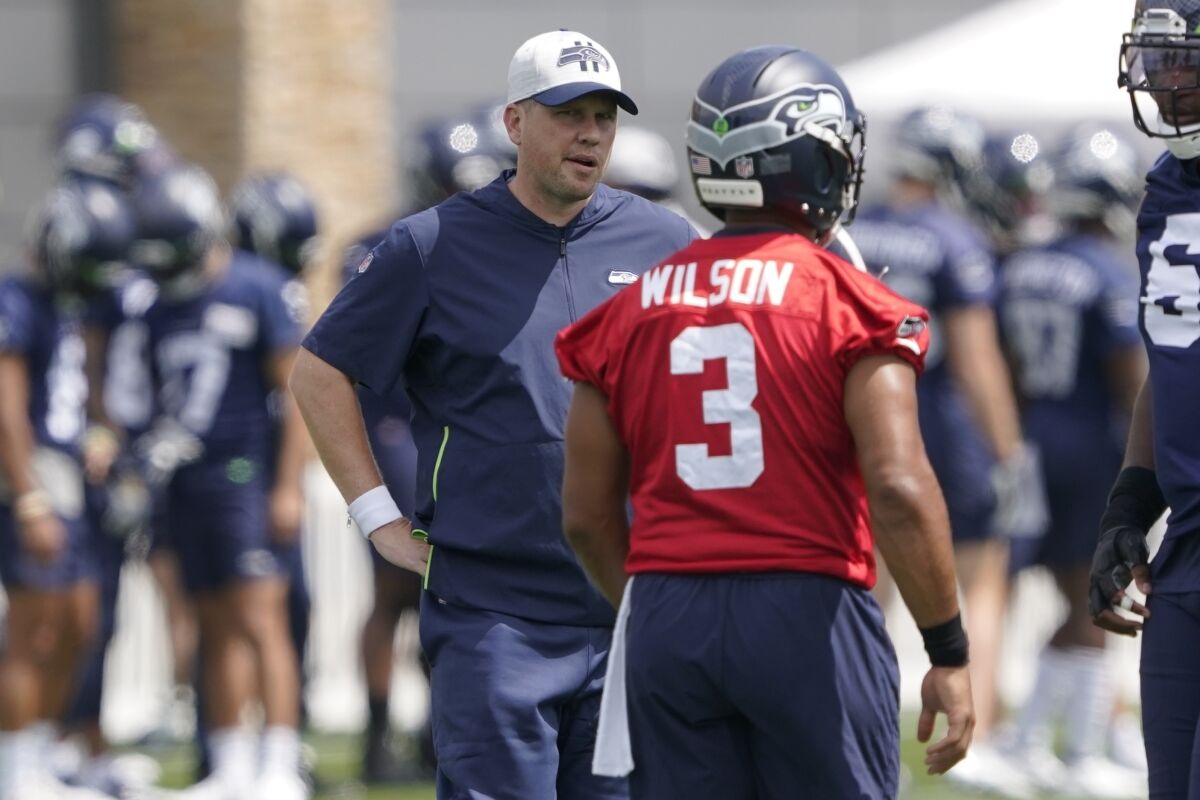 FILE - In this July 28, 2021, file photo, Seattle Seahawks offensive coordinator Shane Waldron, left, talks with quarterback Russell Wilson during NFL football practice in Renton, Wash. When the Seahawks brought Shane Waldron on board as offensive coordinator this offseason, they were hoping to pull some of what worked so well for the division rival Los Angeles Rams and implement it into a system run by Russell Wilson. The test of how well that's worked for Seattle comes on Thursday, Oct. 6, facing the Rams.(AP Photo/Ted S. Warren, File)