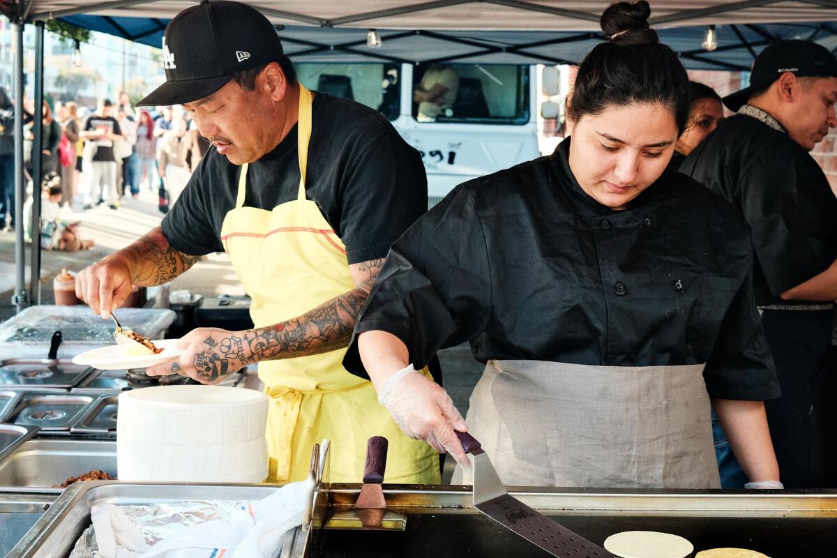 Roy Choi prepares a taco while a member of his team flips tortillas 