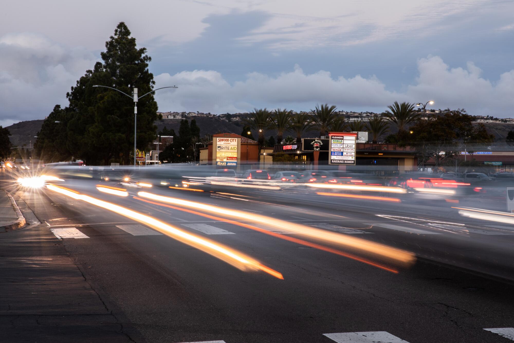 A long-exposure photo of traffic on a busy road at sunset shows red and white streaks from car lights. 
