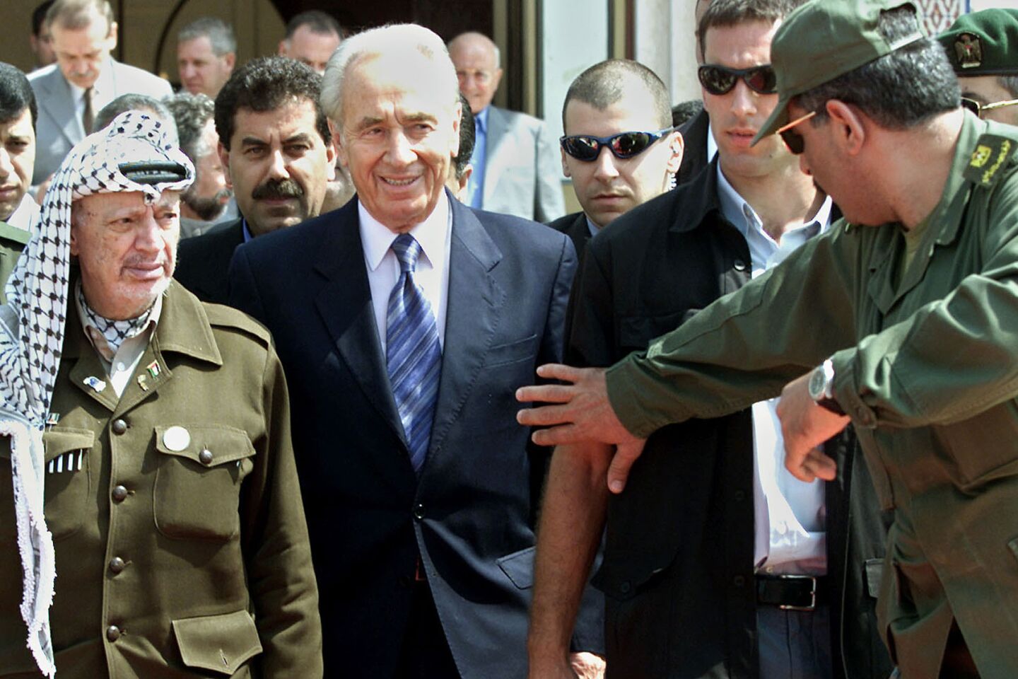 Israeli Foreign Minister Shimon Peres, center, and Palestinian leader Yasser Arafat, left, leave a meeting in the Gaza Strip on Sept. 26, 2001.