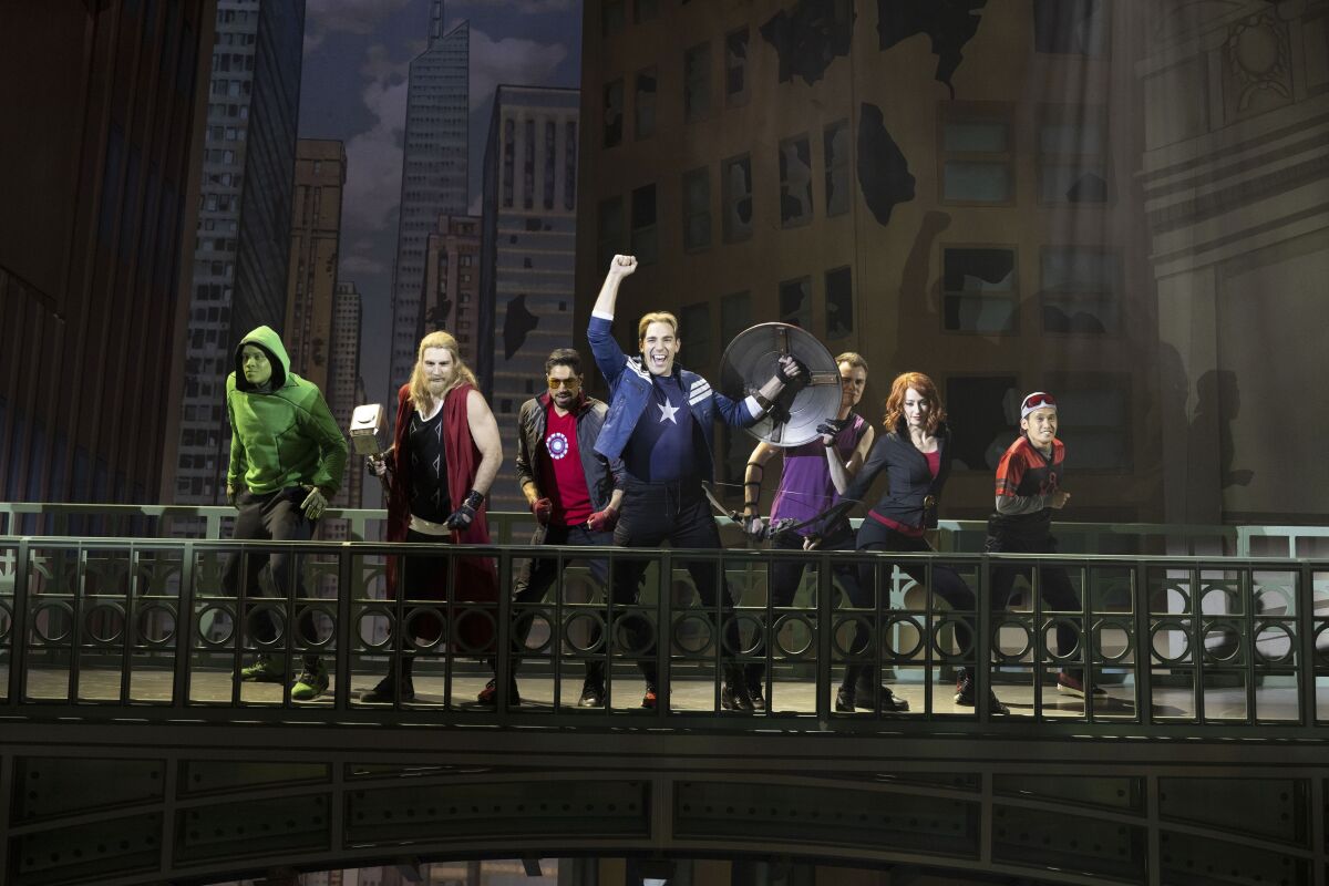 A group of people perform on a stage in superhero costumes