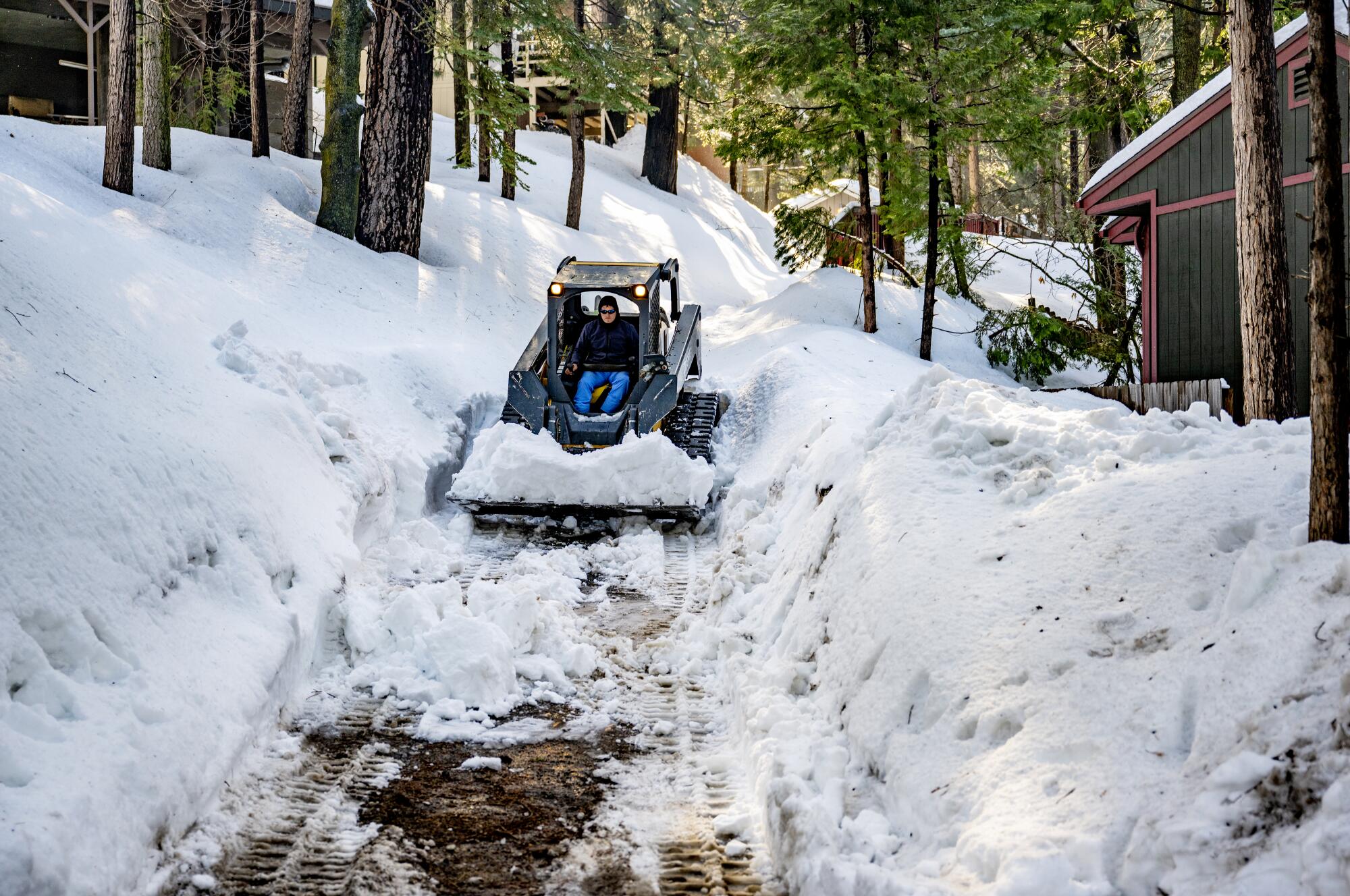 A man drives a tractor amid mounds of snow.