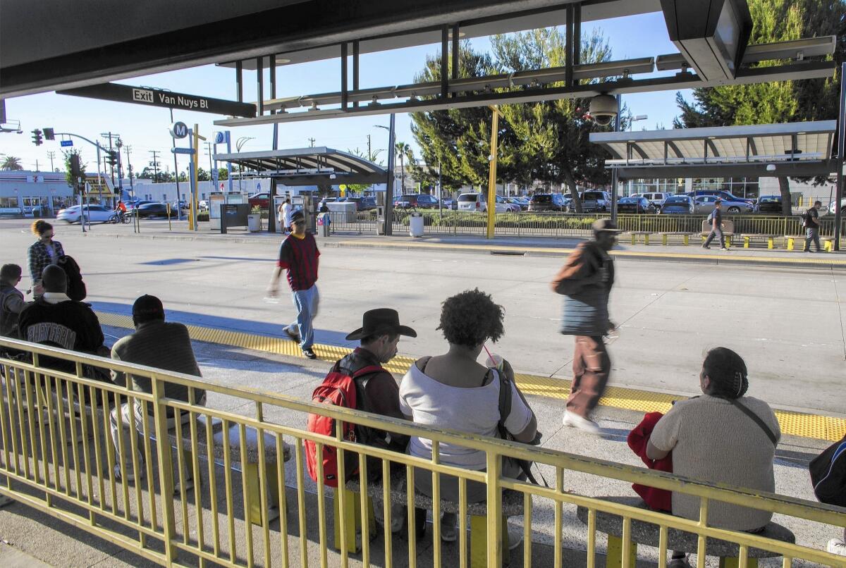 Metro riders wait at an Orange Line station in Van Nuys.