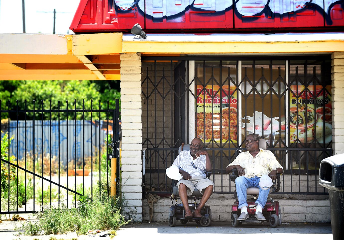 Johnny Lewis, left, and his friend of over 50 years Earl Jackson, right, find refuge in the shade of an abadoned restaurant on Vermont and 54th in Los Angeles on Friday, during the region's latest heat wave.