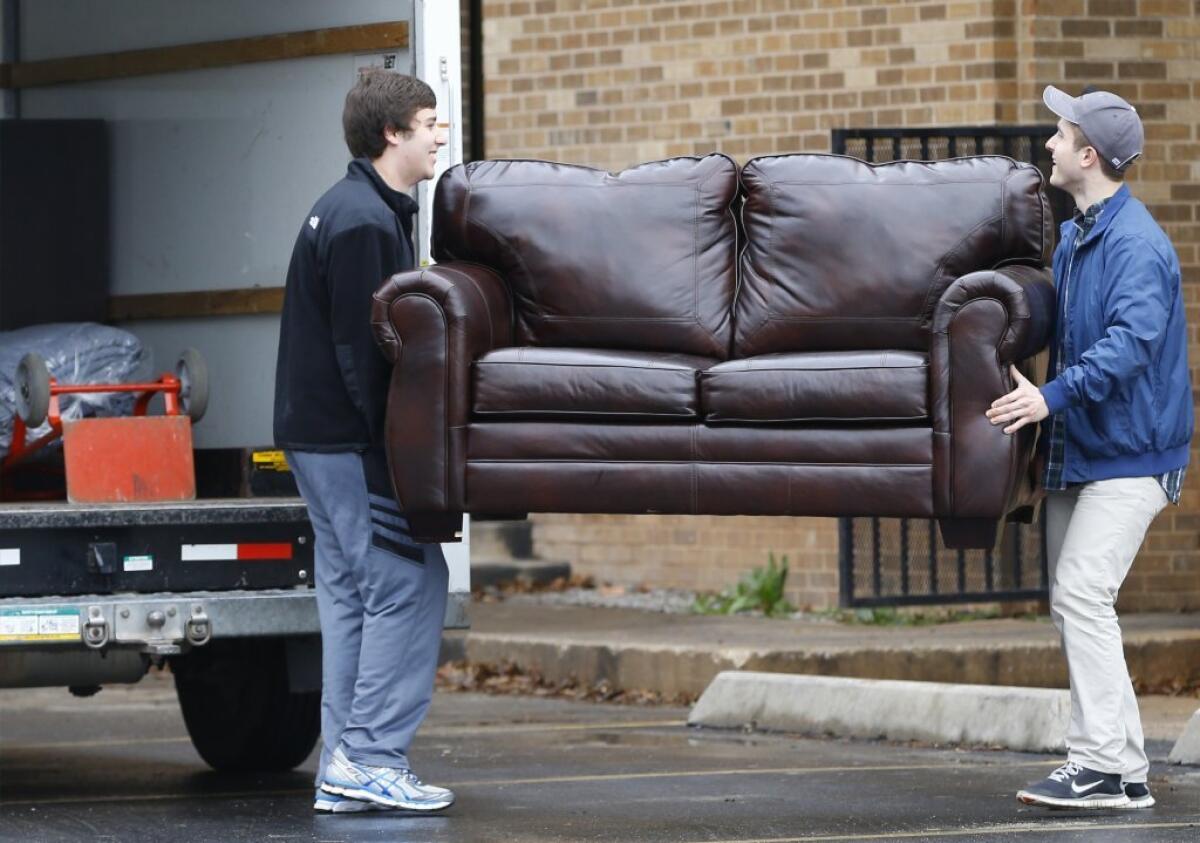 Two men load a couch from the now closed University of Oklahoma's Sigma Alpha Epsilon fraternity house into a moving truck, in Norman, Okla.