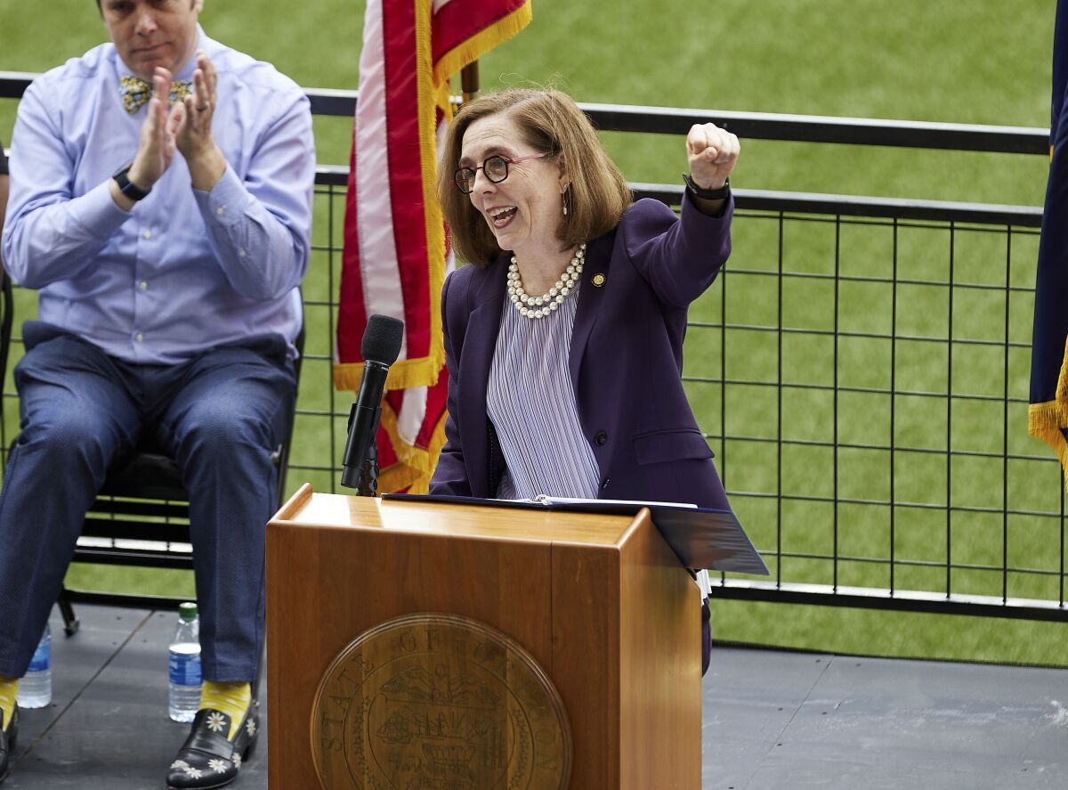 FILE - In this Wednesday, June 30, 2021, file photo, Oregon Gov. Kate Brown pumps her fist while announcing the end of the state's COVID-19 restrictions in Portland, Ore. Brown said Friday, Aug, 13, she will send up to 1,500 National Guard troops to hospitals around the state to assist healthcare workers who are being pushed to the brink by a surge of COVID-19 cases driven by the Delta variant. (AP Photo/Craig Mitchelldyer, File)