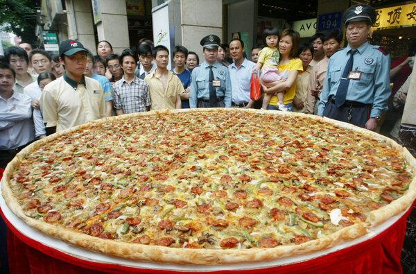 Residents look at a giant pizza with a diameter of 2 meters promoting a U.S. fast food restaurant in Guangzhou, Guangdong province, April 28, 2004.