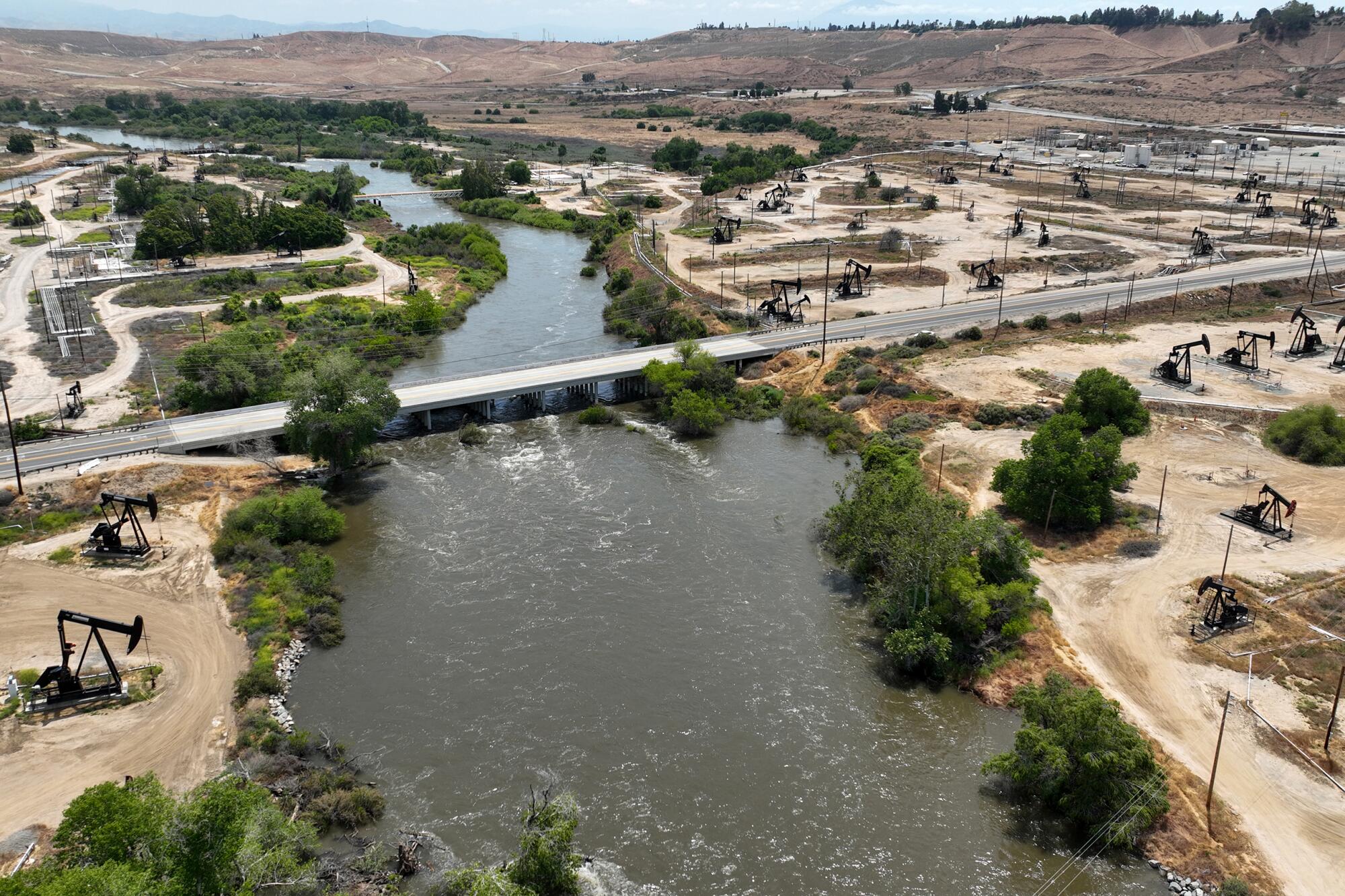 Oil pumpjacks fill the banks of a river. 