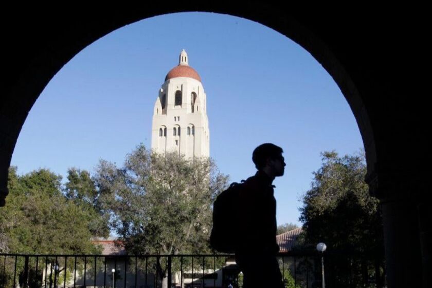 FILE - In this Wednesday, Feb. 15, 2012 file photo, a Stanford University student walks in front of Hoover Tower on the Stanford University campus in Palo Alto, Calif. A mother who says she paid the consultant at the center of the sweeping college admissions bribery scheme $6.5 million says she was duped into believing the money would help underprivileged students. A statement was released Thursday, May 2, 2019 by a Hong Kong lawyer who says he represents the mother. The statement says the consultant, Rick Singer, asked the mother to make a donation through his foundation to Stanford University after her daughter was admitted to the school. (AP Photo/Paul Sakuma, File)